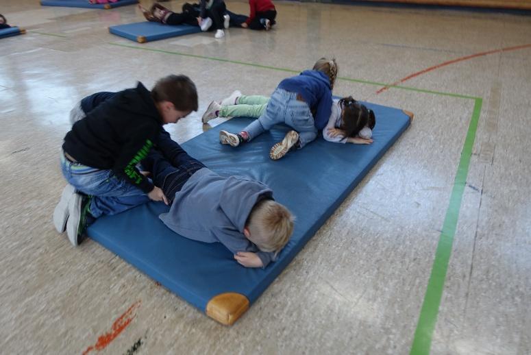 Kinder üben pädagogisches Matten raufen auf einer Turnmatte